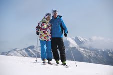 Skiers atop Hotham with Mount Feathertop background.